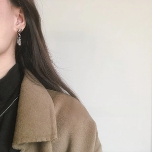 Close-up of a silver letter tassel chain earring worn by a model in profile view