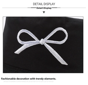Detail view of stylish white embroidered bow on black cotton reversible bucket hat