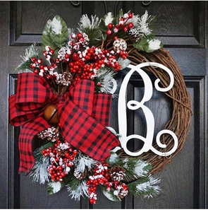 Detail of Christmas wreath with red plaid bow, red berries, pine cones and golden bell