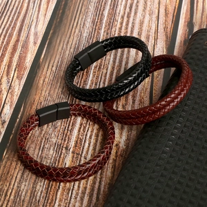 Braided leather bracelets in black and burgundy with magnetic clasps on wood surface
