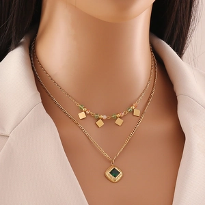 Double-layered gold star necklace with green crystals and small beads on model