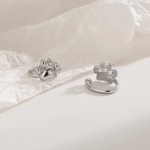 Detail view of silver cat paw clip earrings featuring smooth polish and hollow texture