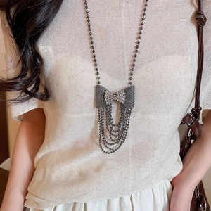 Detail of a dark metal bow pendant necklace with sparkling rhinestones and beaded tassels