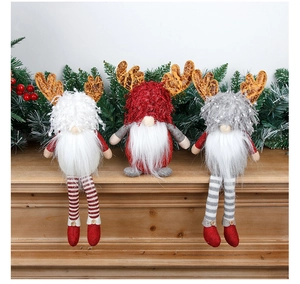 Three Christmas gnomes with reindeer antlers sitting on a mantel with festive greenery