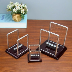Three sizes of classic metal Newton's cradle balance balls on dark wooden base