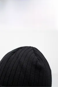 Nahaufnahme des groben Rippstrickmusters der schwarzen Wintermütze für Herren