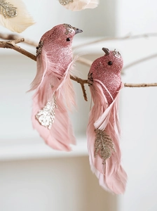 Pájaro decorativo rosa con lentejuelas y plumas sobre rama de madera natural
