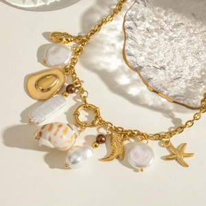 Gold necklace with baroque pearls, cowboy boots, shells and starfish charms in sunlight
