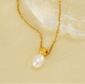 Detail of elegant gold-toned pearl necklace with a hammered texture metal bead and drop pearl