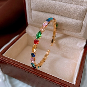 Detail of vintage gold textured cuff bracelet featuring multicolored gemstones in a jewelry box