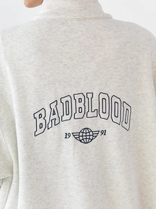 Close-up of gray sweatshirt fabric with BADBLOOD embroidery and 1991 earth logo detail