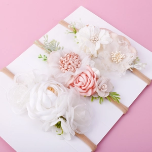 Detailed view of three elastic baby headbands with delicate fabric flowers on white card