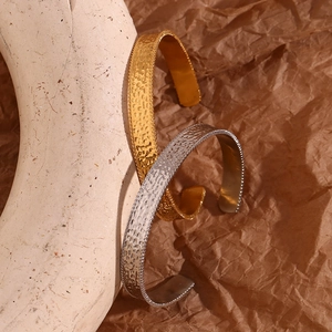 Detailed close-up of hammered texture on gold and silver open bangles over paper