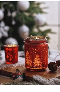 Close-up of a red glass Christmas candle holder with LED lights and festive patterns
