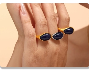 Three gold and silver water drop rings with blue resin stones worn on hand