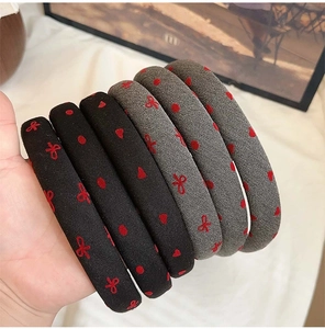 Close-up of black and grey polka dot heart bow headbands held in hand detail