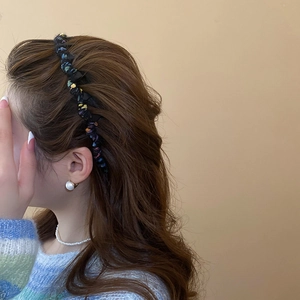 Detail of colorful woven wool wavy headband on model with elegant pearl accessories