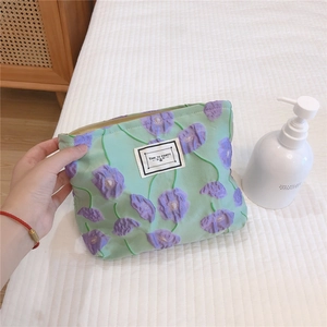 Macro detail of mint green pouch with purple flower embroidery and metal zipper