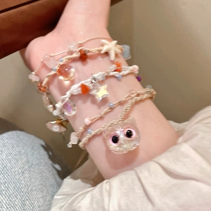 Close-up of handmade woven bracelet with colorful starfish and seashell charms on wrist