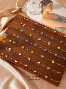 Detail of colorful beaded flower bracelets with 18K gold plated chains on wood display