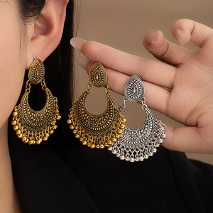 Detail view of retro bohemian half-moon earrings with floral carvings and beads