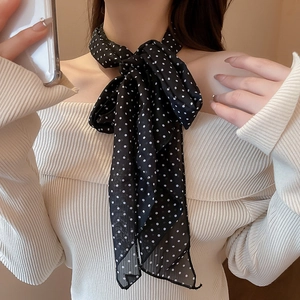 Detailed shot of a black polka dot silk scarf tied stylishly around a woman's neck