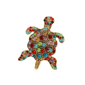 Détail macro d'une broche tortue de mer dorée ornée de strass multicolores