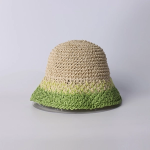 Dettaglio del cappello a secchiello in paglia fatto a mano con trama sfumata beige e verde