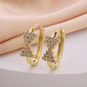 Elegant gold bow earrings with cubic zirconia stones on white display stand