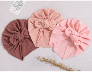 Detailed view of three baby turban hats in pink shades with knit texture and cute bows