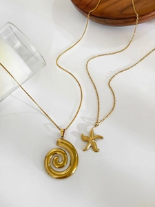 Detail of 18k gold plated starfish and seashell necklaces on minimalist white background