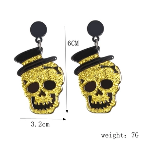 Detail view of glittery gold skull earrings with black hats and size dimensions