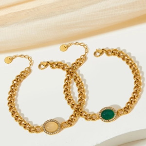 Detailed close-up of emerald and ruby agate gold bracelets on elegant silk background