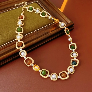 Détail d'un collier vintage avec perles et pierres vertes sur fond en bois