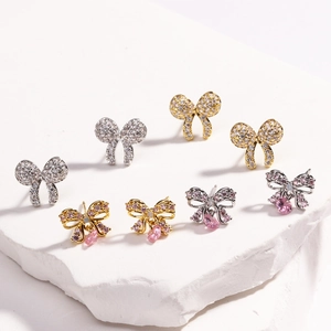 Detailed view of colorful zircon bow earrings with pink heart droplets on stone base