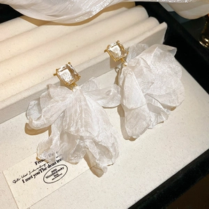 Detailed macro of white fabric floral earrings with sparkling square crystals