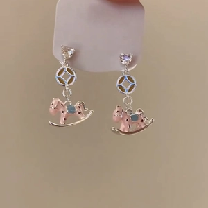 Detail of pink enamel rocking horse pendant earrings with heart rhinestone studs