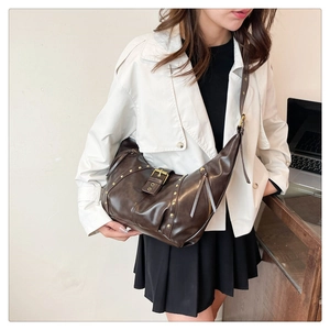 Detail der dunkelbraunen Hobo-Tasche mit Goldnieten, Schnalle und Lederstruktur
