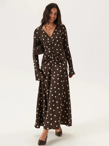 Détail de robe longue marron à pois avec col en V, taille froncée et manches évasées