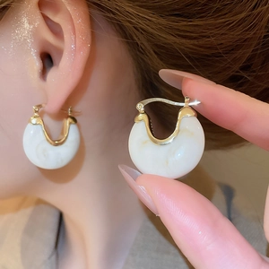 Détail de boucles d'oreilles vintage en résine en U avec base en métal doré texturé
