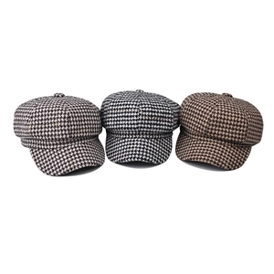 Detailed close-up of three houndstooth newsboy caps in grey, black, and brown textures