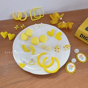 Ensemble de boucles d'oreilles fleurs jaunes et géométriques sur assiette blanche