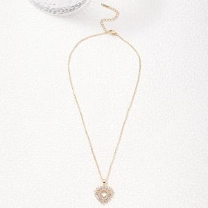 Golden heart pendant necklace with shimmering white zircon crystals on a white textured backdrop