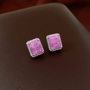 Macro shot of silver stud earrings with pink rectangular zircon and crystal halo