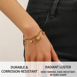 Detail of gold-plated stainless steel bracelet with heart and flower charms on a wrist