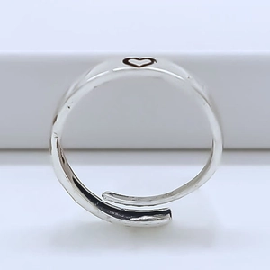 Macro detail of silver heart-shaped cutout ring with an adjustable open-band design