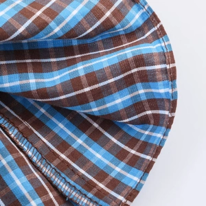 Dettaglio del tessuto a quadri blu e marroni con cuciture di pregio sul vestito
