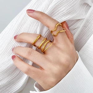 Detailed view of two layered gold wave rings with elegant twisted lines on fingers