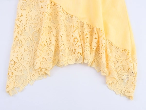 Detail of yellow sleeveless top with delicate lace patchwork and scalloped floral hem