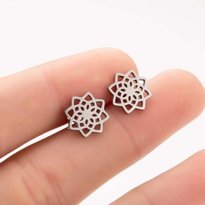 Minimalist silver stainless steel hollow flower stud earrings held on a finger for scale